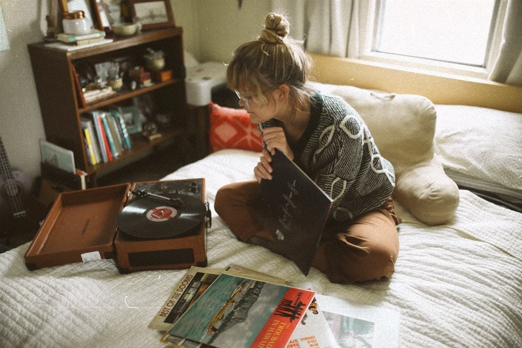 Image of girl sitting cross legged on her bed surrounded by books. 